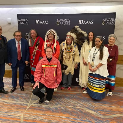 Kectil participants in traditional dress posing at an event backdrop.