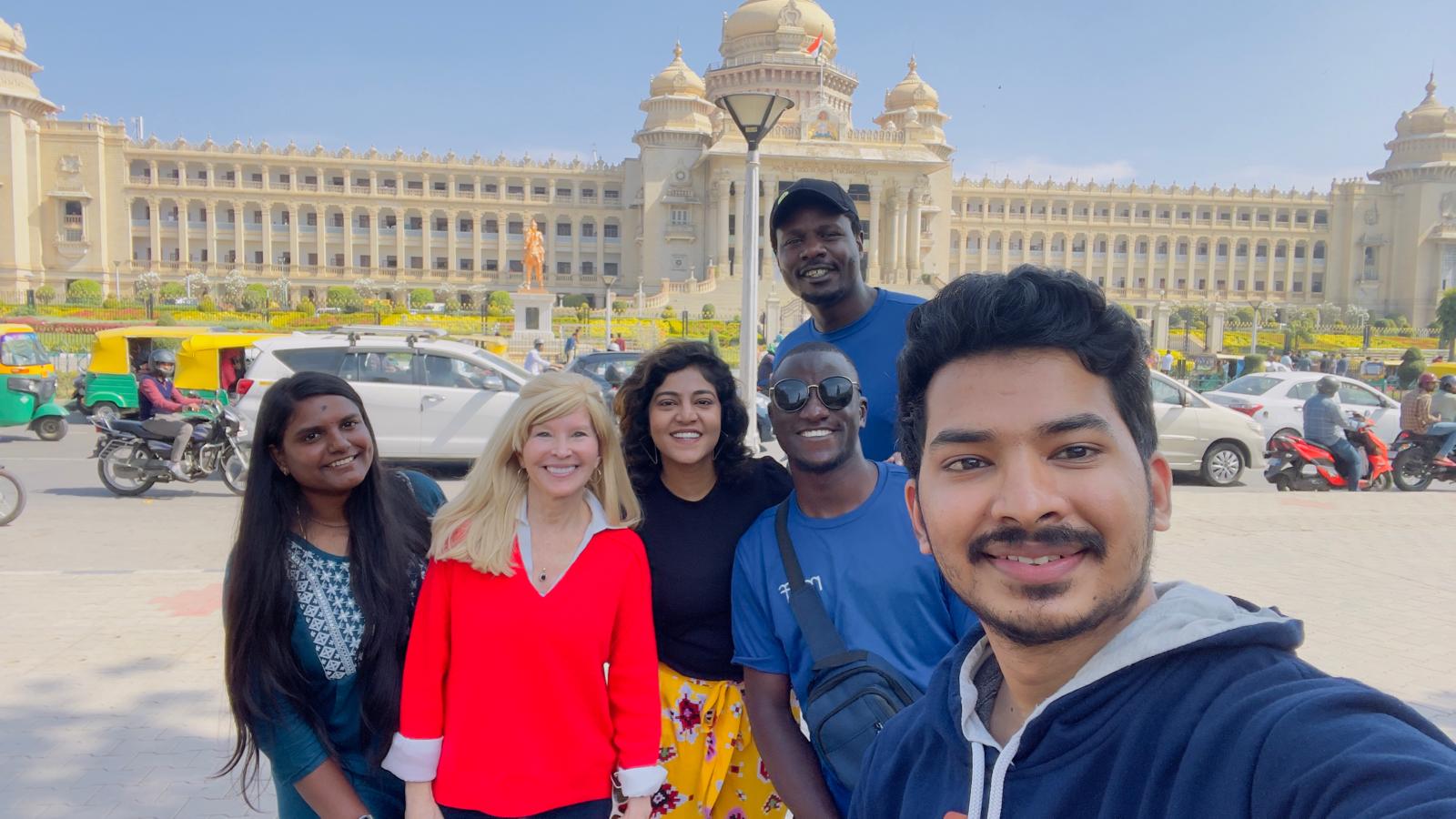 Kectil participants taking a group selfie near a government building in India.
