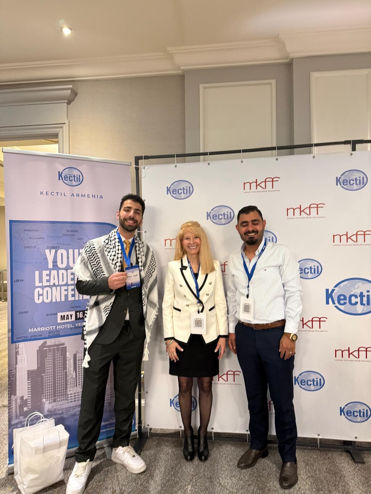 Kectil colleagues standing together at a program conference backdrop.